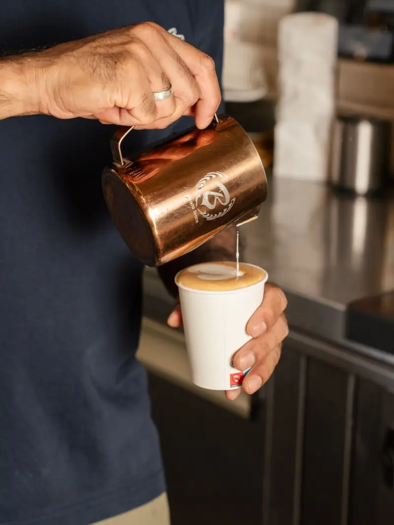 Un barista verse le lait dans un café à emporter