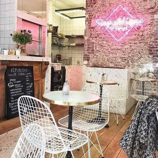 La salle avec son mur de briques roses, son néon et ses chaises en fil blanc