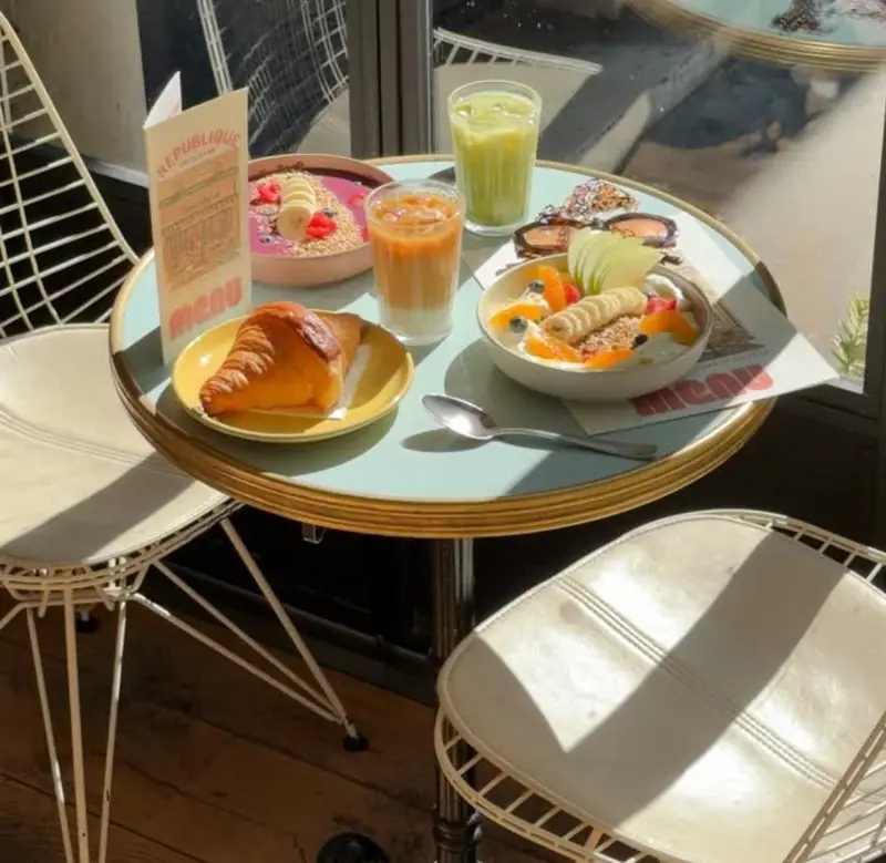 Table de brunch en terrasse au soleil, jus et viennoiseries